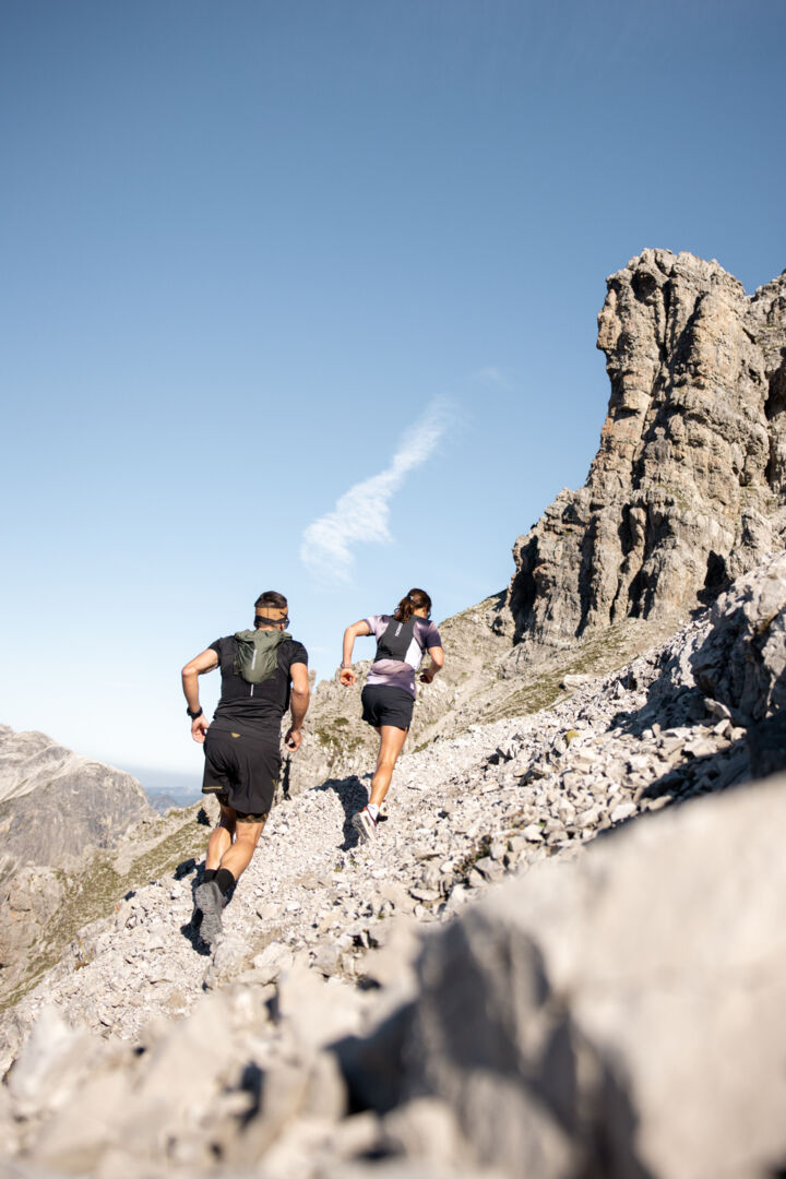 Zwei Trailrunner laufen einen steinigen Pfad hinauf