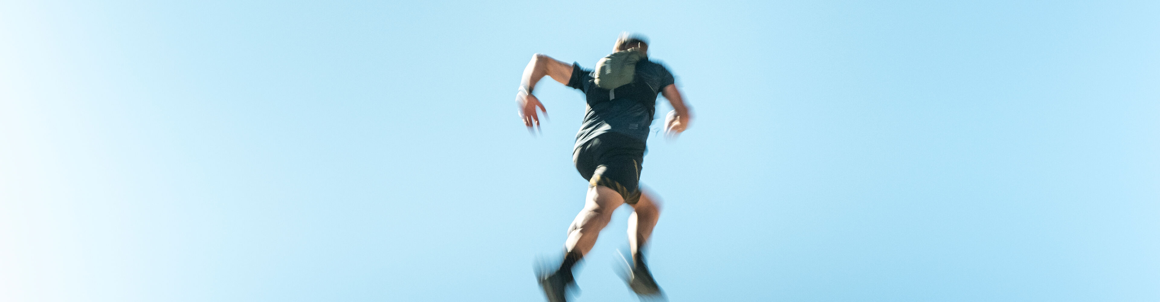 Trailrunner läuft dynamisch am Fels bergauf